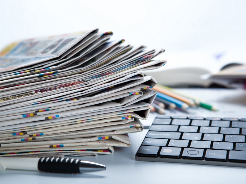 stack of newspapers and keyboard close-up on white